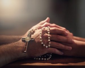 Man holding white rosary beads in his hand