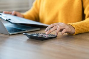 Woman in yellow sweater using a calculator to determine insurance amount