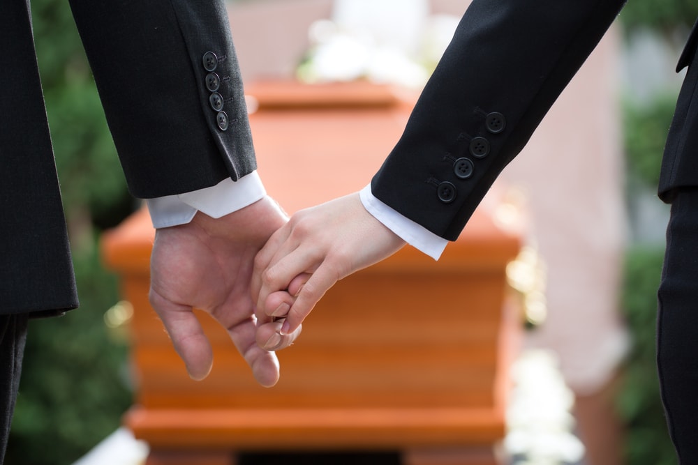Two people holding hands as they participate in the elements of a funeral