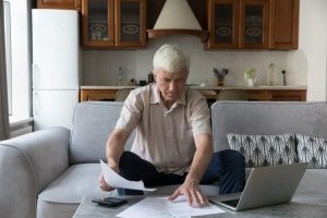 Man sitting on couch at home as he sorts through documents