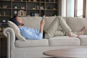Man laying on couch and listening to music to relax