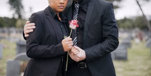 Man and woman grieving together and holding a single pink rose
