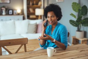 Woman in blue shirt sitting on home and talking on the phone