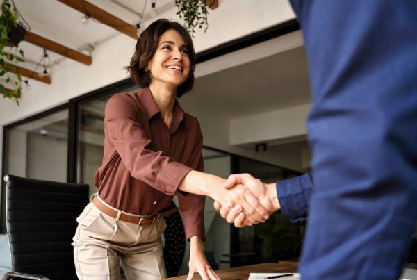 Man and woman greeting each other with a handshake in a professional setting