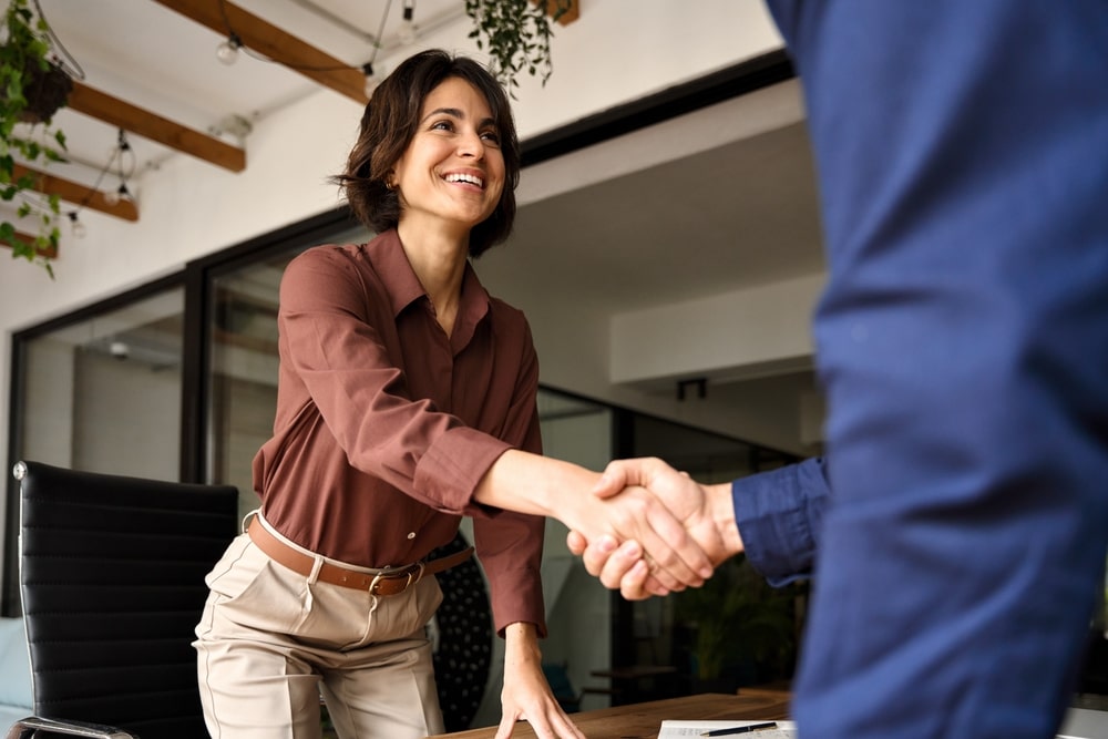 Man and woman greeting each other with a handshake in a professional setting