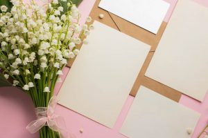 Ivory paper with pink envelopes and a small bouquet of white flowers
