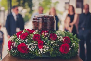 Urn sitting on table with red rose floral arrangement 