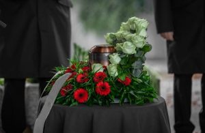 Copper urn sitting on a table, nestled in white roses and red flowers