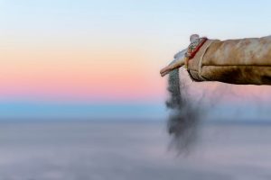 Person releasing ashes against a rainbow sky