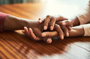 Two people holding hands in a comforting manner