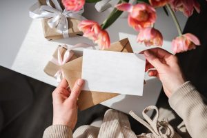 Person holding a folded piece of paper and envelope with pink flowers