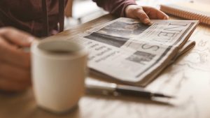 Man with coffee mug reading newspaper