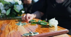 Woman placing a white rose on a casket at a funeral