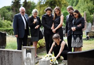 Family gathering around a loved one's grave and placing a memorial wreath on it