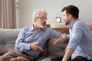 Senior man sitting on couch and talking with adult son