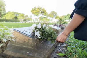 Woman in black dress placing white flowers on an urn burial site