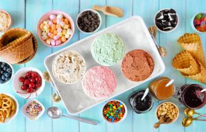 Ice cream buffet with four flavor cartons, cones, and toppings