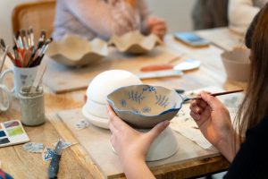 Woman painting on a piece of pottery