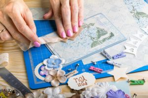 Person creating a scrapbook page with supplies