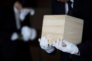 Wooden urn box carried by a man in white gloves