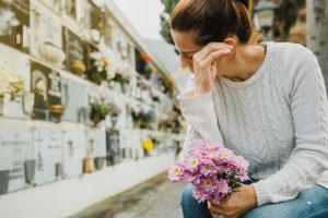 Sad woman taking pink flowers to a loved one's final resting place at a columbarium