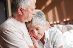 Senior husband comforting his grieving wife with a hug