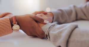 Two friends holding hands as they comfort each other