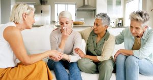 Group of four women on a couch, comforting a crying friend