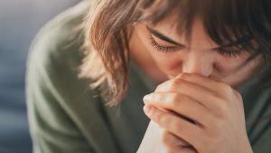 Close-up on girl in green shirt crying with tears in her eyelashes