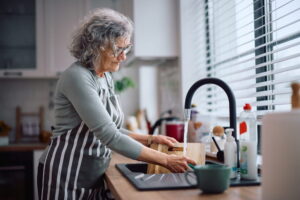 Senior woman washing dishes to help around the house