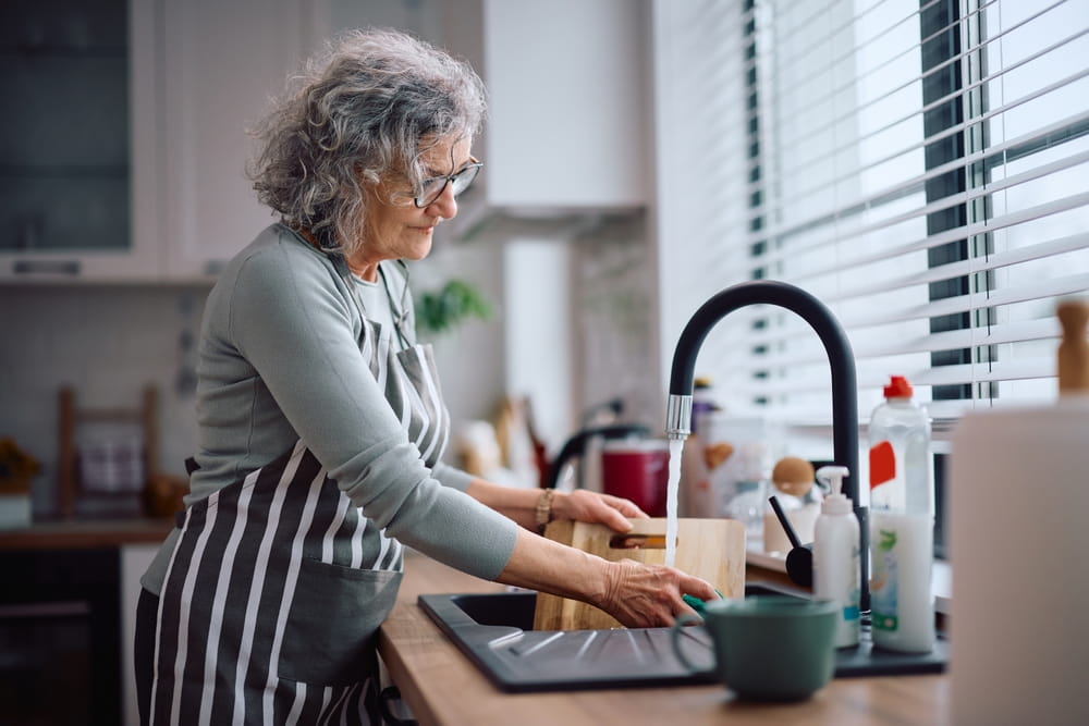 Senior woman washing dishes to help around the house