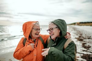 Two women in colorful rain jackets talking on a beach