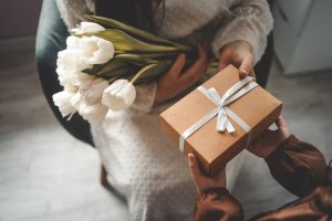 Friend giving a sympathy gift and flowers to a grieving friend