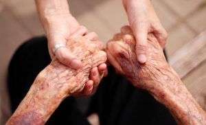 Younger person holding the hands of an older person in a comforting way