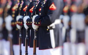 Line of marines in dress uniform holding rifles at attention