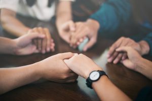 Group of people holding hands in prayer