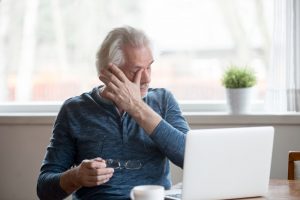 tired older man wiping his eyes