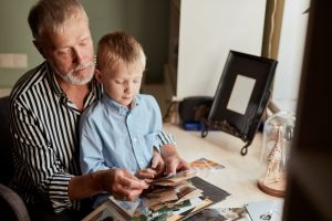 Man holding child on his lap as they look at photographs