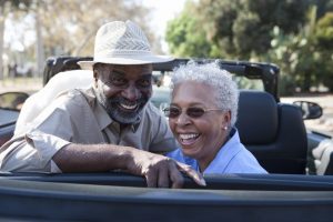 Older couple sitting in a convertible smiling at the camera