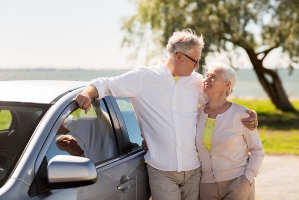 Older couple standing next to car looking lovingly at each other