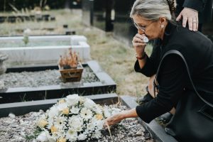 Mature mothing laying wreath on grave