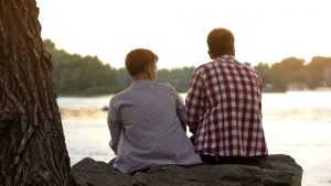 Father and son sitting outside looking at lake