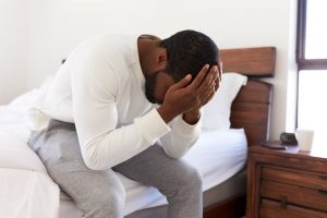 Man sitting on bed with head in hands