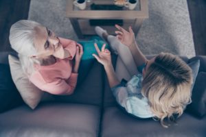 Downward angle, mom and adult daughter siting on couch, talking