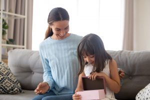 Little girl opening small memory capsule with her mom beside her