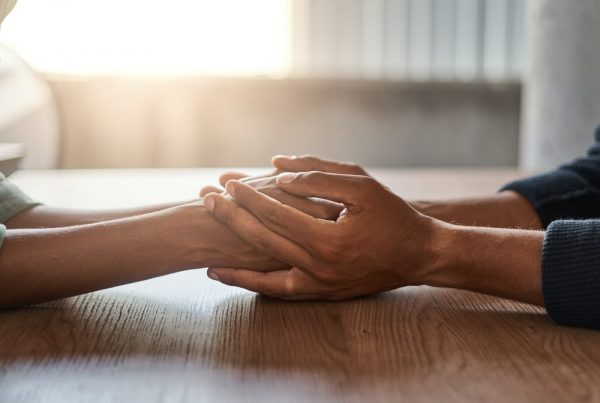 Two people holding hands across table, no faces