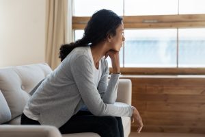 sad woman sitting at home looking out window