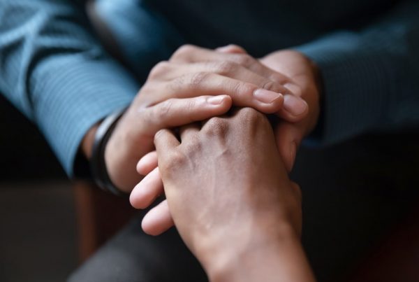 Two people holding hands in a comforting way