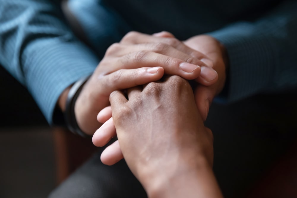 Two people holding hands in a comforting way