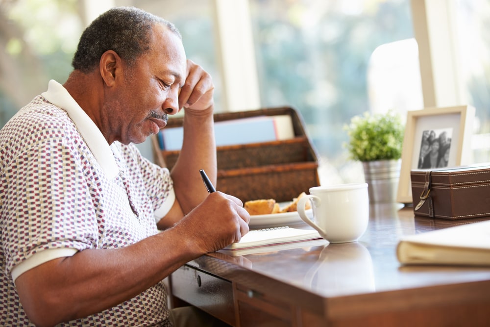 Older man sitting at desk writing letters